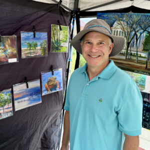 Artist David Goldstein with his paintings in a booth at the Mason District Arts Festival on October 11, 2025.