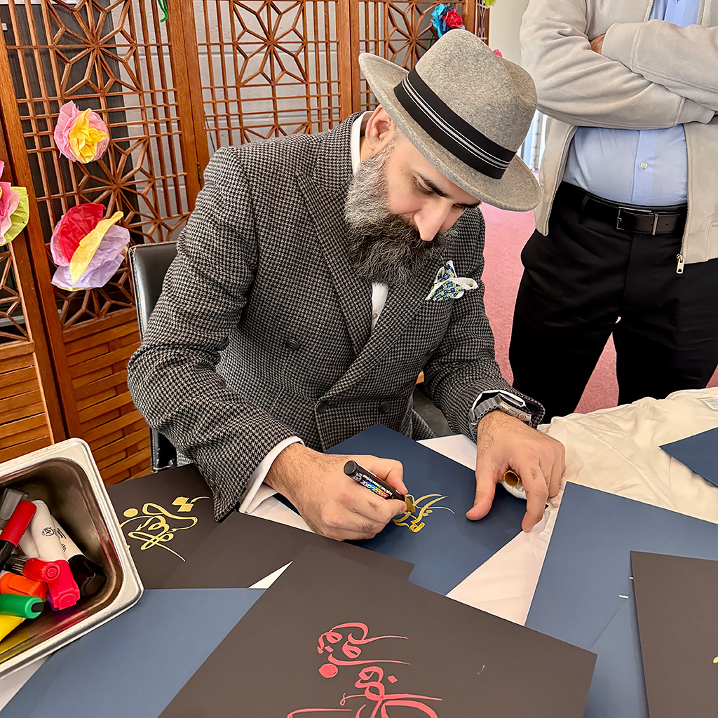 Sulieman Hedayat writes the names of attendees as part of a calligraphy demonstration during the Nowruz celebration on March 21, 2026 at John Calvin Presbyterian Church in Annandale, VA.