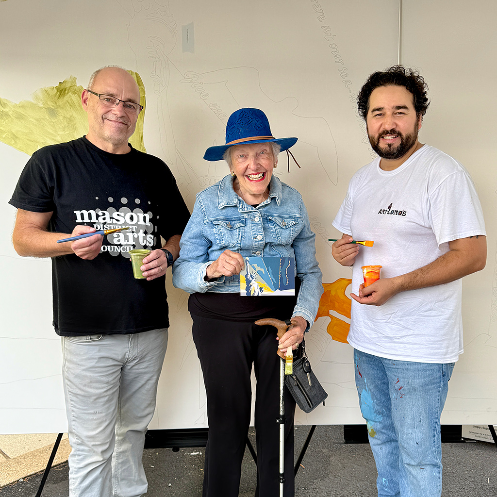 Mason District Arts Council chair, James Albright; former Mason District Supervisor Penny Gross; Omaid Sharifi, President of ArtLords pose at the start of the community mural project staged as part of the Mason Arts 250 series of activities to commemorate America's 250 founding anniversary.