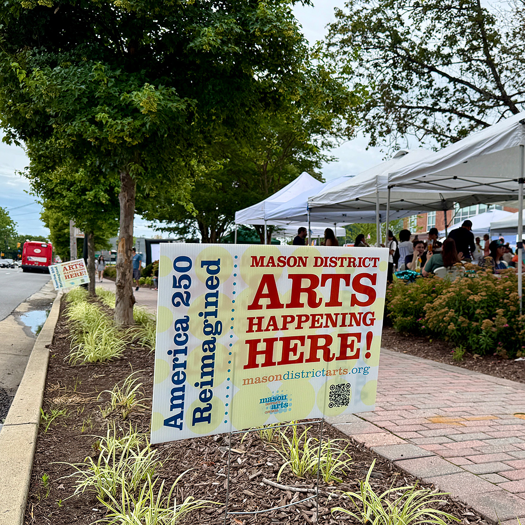 Roadside signs promoting the Mason District Arts Council community mural project and Wishing Tree event staged as part of the Mason Arts 250 series of activities to commemorate America's 250 founding anniversary. The final Mason Arts 250 event was held on June 27, 2026 in connection with the DMV Night Market.