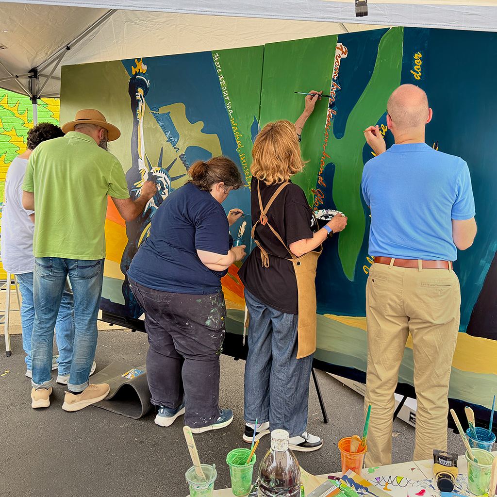 Volunteers work on the community mural for the Mason District Arts Council as part of the Mason Arts 250 series of activities to commemorate America's 250 founding anniversary.
